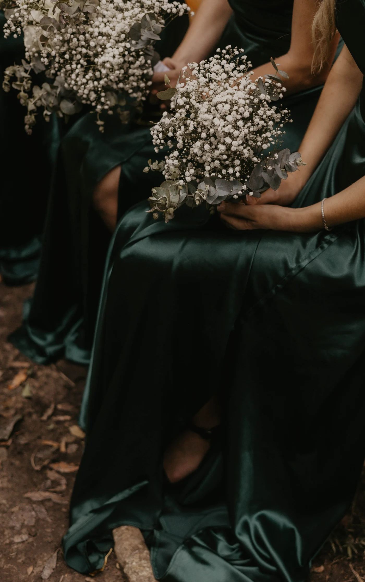 Bridesmaids in emerald green holding white bouquets
