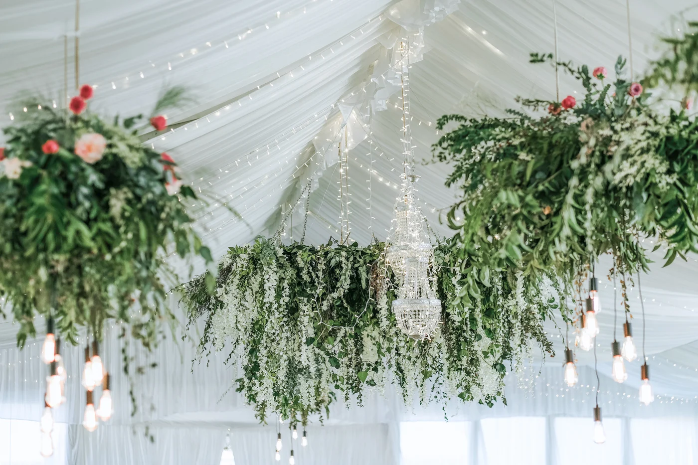 Hanging greenery and floral arrangements in a marquee