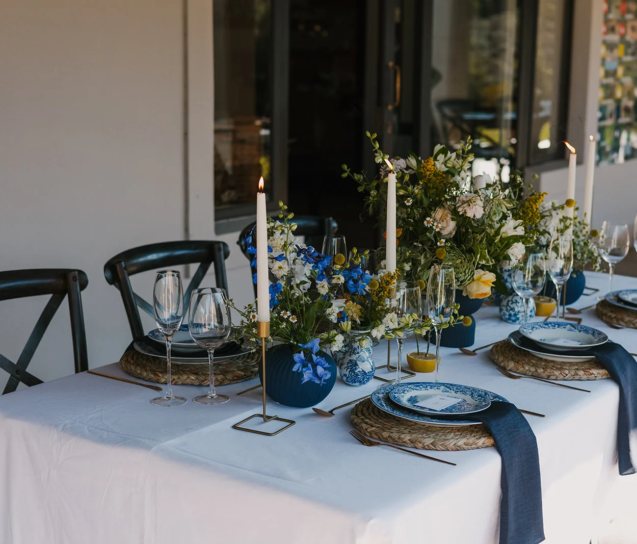 Blue and yellow floral tablescape with candles and blue patterned plates